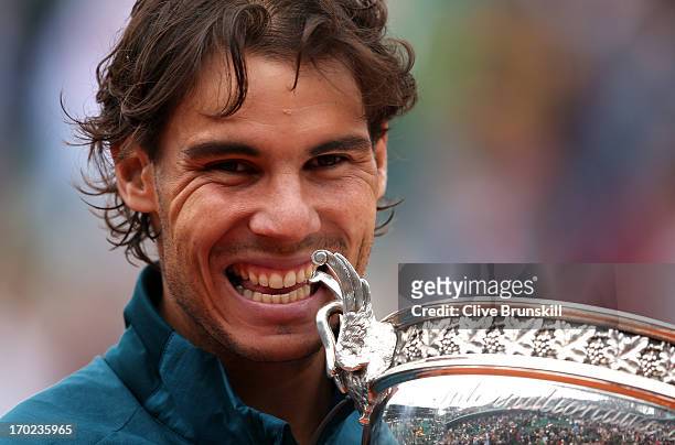 Rafael Nadal of Spain bites the Coupe des Mousquetaires trophy as he celebrates after the men's singles final against David Ferrer of Spain during...