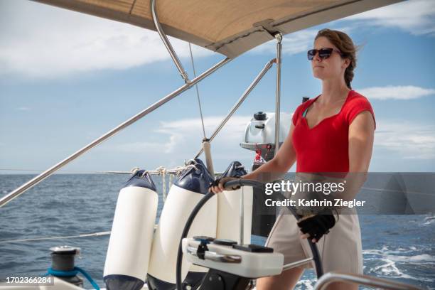 female crew member steering yacht - kapitein stockfoto's en -beelden