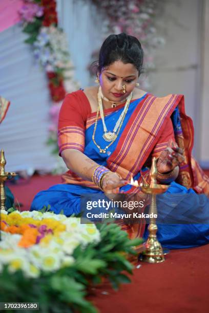 woman lighting oil lamp(diya) sitting in front of shivlingam - oil lamp stock pictures, royalty-free photos & images