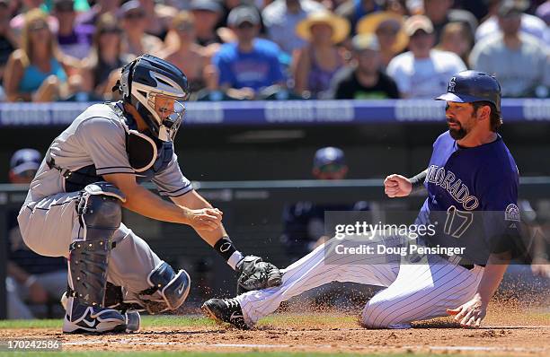 Catcher Nick Hundley of the San Diego Padres tags out Todd Helton of the Colorado Rockies at home as he tries to score on a fly ball by Jonathan...