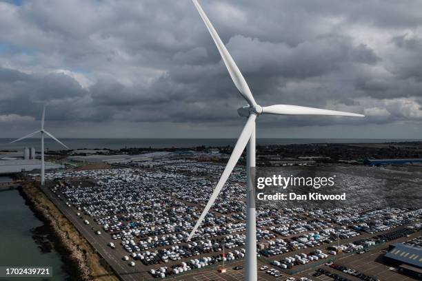 Newly imported cars sit at the Peel Ports London Medway facility besides a wind turbine on September 26, 2023 in Sheerness, United Kingdom.