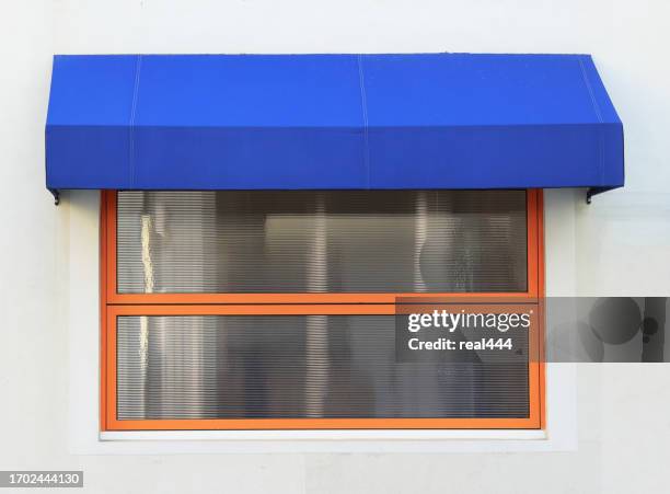 toldo azul sobre la ventana de los residentes - awning window fotografías e imágenes de stock