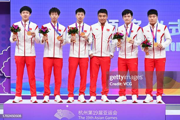 Gold medalists Wang Chuqin, Lin Gaoyuan, Ma Long, coach Wang Hao, Fan Zhendong and Liang Jingkun of Team China pose during the medal ceremony for the...