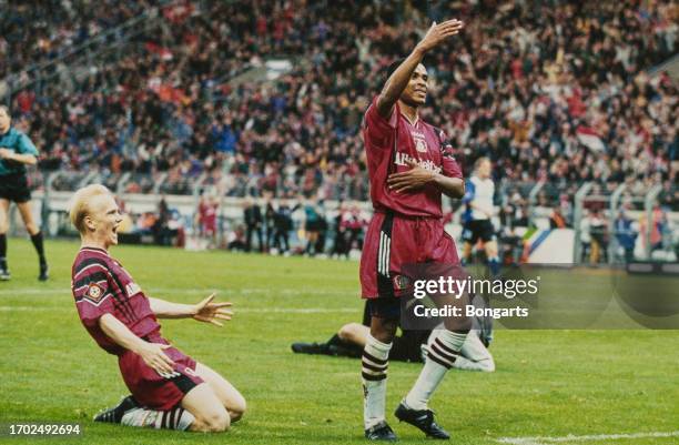 German footballer Carsten Ramelow on his knees as Brazilian footballer Paulo Sergio celebrates after scoring Bayer Leverkusen's fifth goal during the...