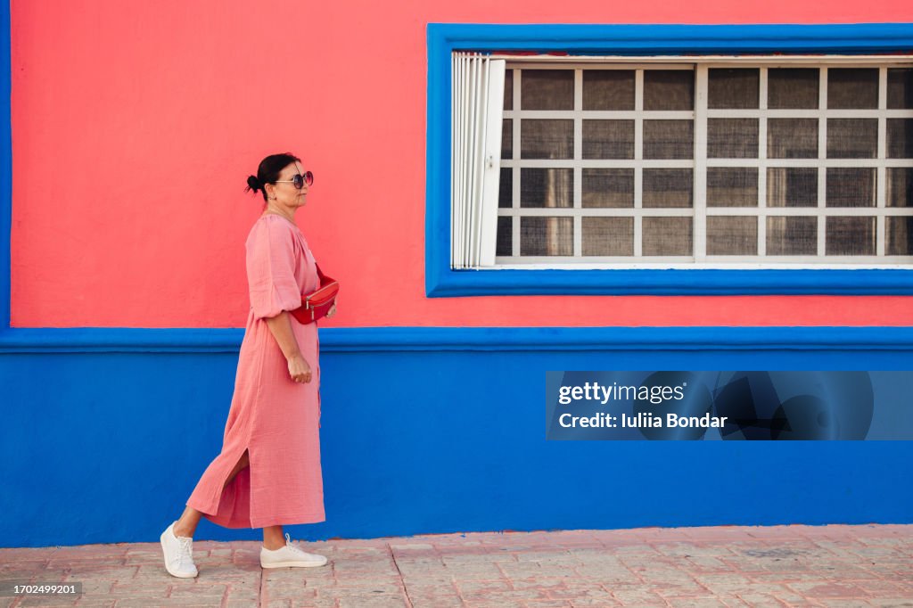 Middle-age woman walking on a colorful street in Mexico