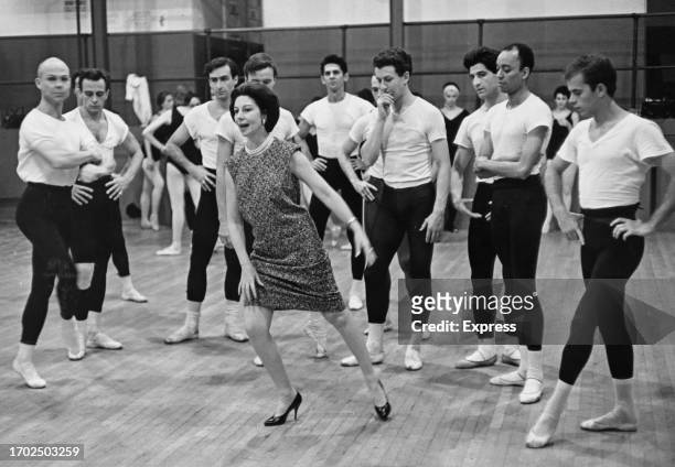 British ballerina and choreographer Alicia Markova demonstrating a dance step to a group of male ballet dancers, with ballerinas in the background,...
