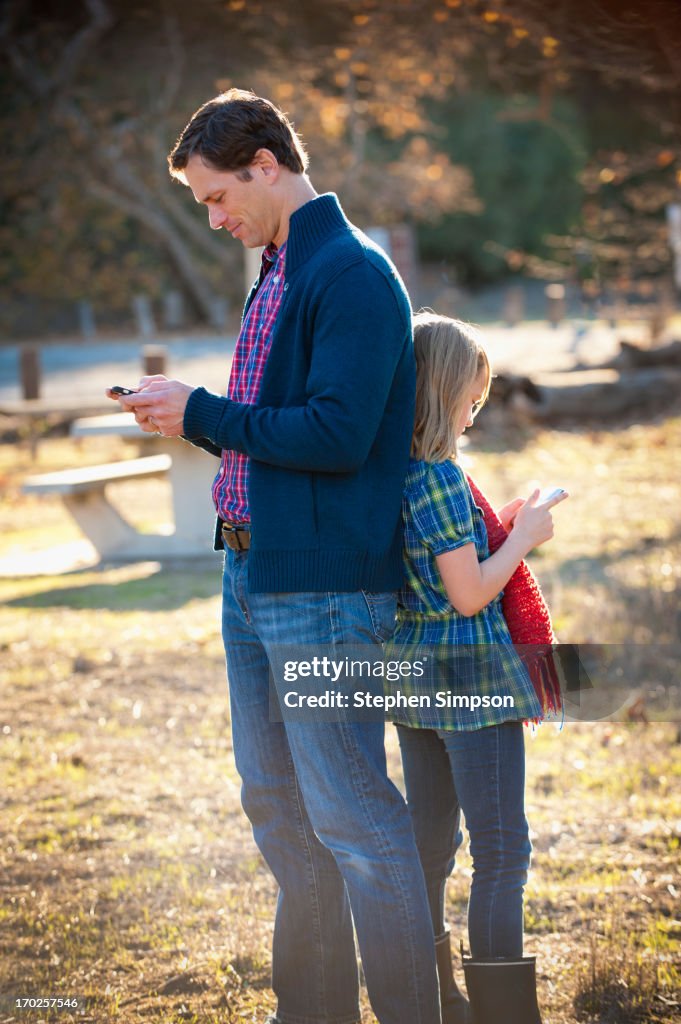 Father and daughter back to back on cell phones