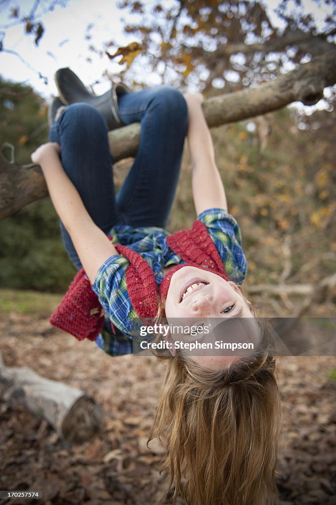 Fall, girl hanging upside down from tree branch