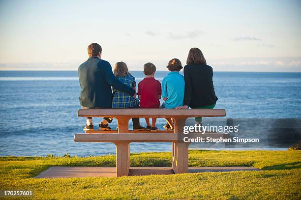 family on picnic bench by the ocean - familia con tres hijos fotografías e imágenes de stock