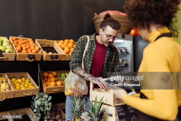 mann kauft lebensmittel mit hilfe einer verkäuferin - klein stock-fotos und bilder