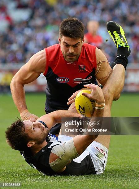 Nathan Brown of the Magpies handballs whilst being tackled by Chris Dawes of the Demons during the round 11 AFL match between the Melbourne Demons...