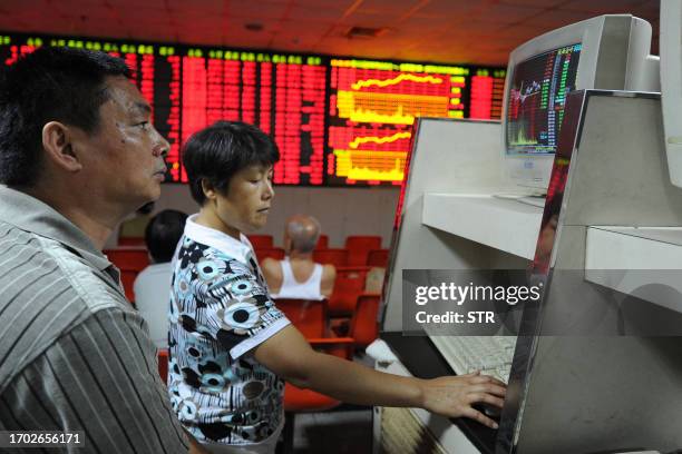 Chinese investors check their stock prices at a securities firm in Hefei, east China's Anhui province on July 7, 2011. Asian stocks were mixed in...