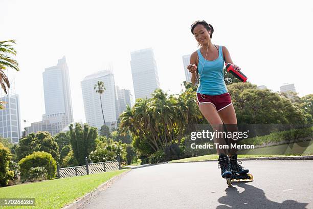 woman on inline skates looking at mp3 player - skaten stockfoto's en -beelden