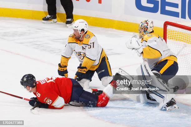 Dante Fabbro of the Nashville Predators checks Mike Reilly of the Florida Panthers to the ice in front of goaltender Troy Grosenick during a...