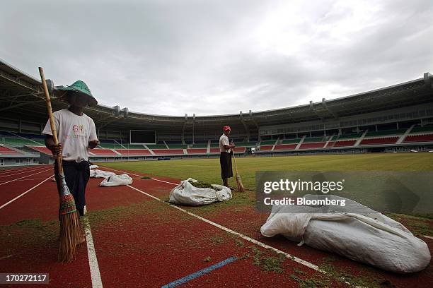 Workers sweep grass clippings off the running track inside the Wunna Theikdi Football Stadium, part of the Wunna Theikdi Sports Complex developed for...