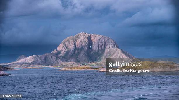 a mountain with a hole through to the other side - baai stockfoto's en -beelden