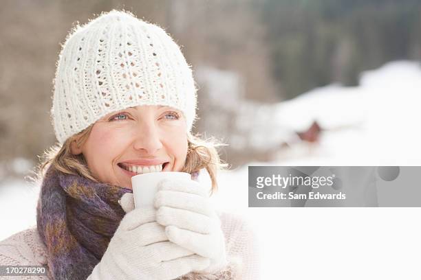 woman drinking coffee outdoors in snow - middle aged woman winter stockfoto's en -beelden