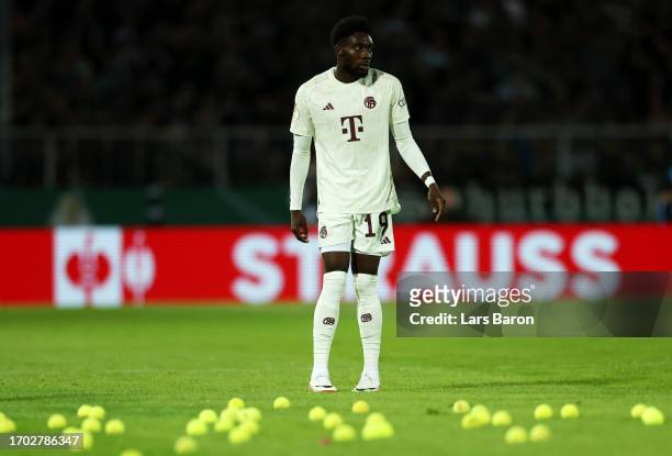 Alphonso Davies of Bayern Munich reacts as tennis balls are thrown onto the pitch by fans of Bayern Munich during the DFB cup first round match...