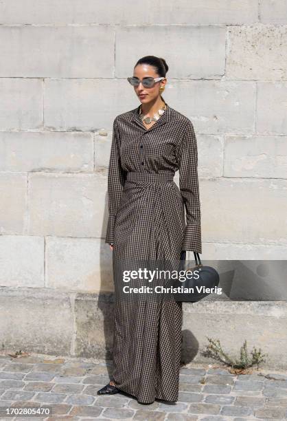 Bettina Looney wears checkered overall, black bag, sunglasses, necklace outside Dior during the Womenswear Spring/Summer 2024 as part of Paris...