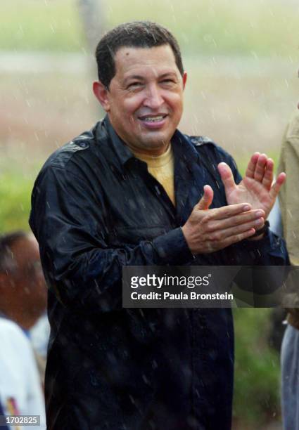 President Hugo Chavez applauds in the rain at a fuel distribution plant located 93 miles east of Caracas December 27, 2002 in Carenero, Venezuela....