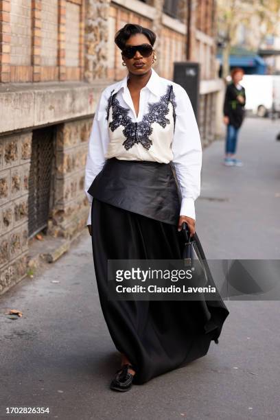 Guest wears a white shirt, cream top with lace details, back maxi skirt with leather detail and black bag, outside Victoria/Tomas, during the...