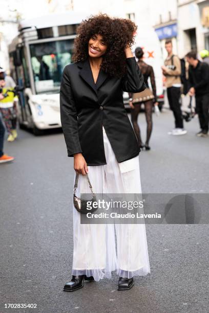 Guest wears a black blazer, white tulle maxi skirt, bronze mini bag and black shoes, outside Victoria/Tomas, during the Womenswear Spring/Summer 2024...