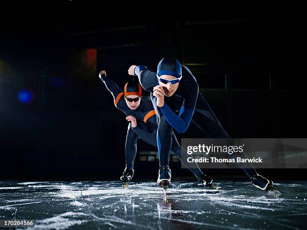 two long track speed skaters racing on track - indoor skating stock pictures, royalty-free photos & images