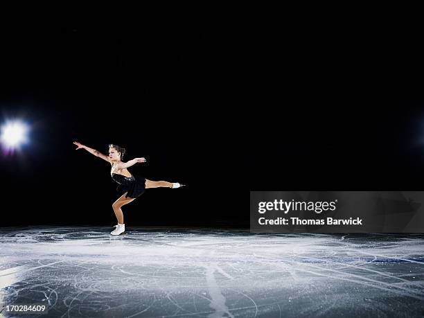 figure skater landing a jump during a performance - patinaje sobre hielo fotografías e imágenes de stock