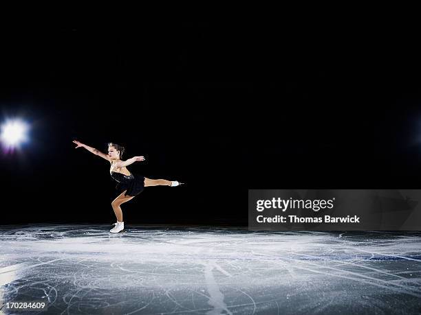 figure skater landing a jump during a performance - patinaje artístico fotografías e imágenes de stock