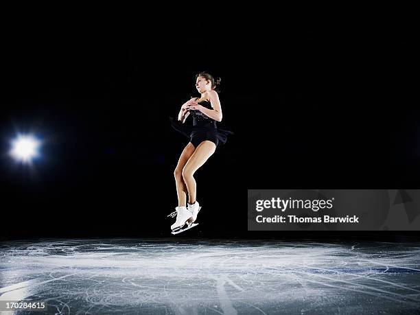 female figure skater jumping in mid air - pista di pattinaggio su ghiaccio foto e immagini stock