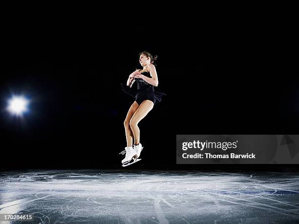 female figure skater jumping in mid air - フィギュアスケート ストックフォトと画像