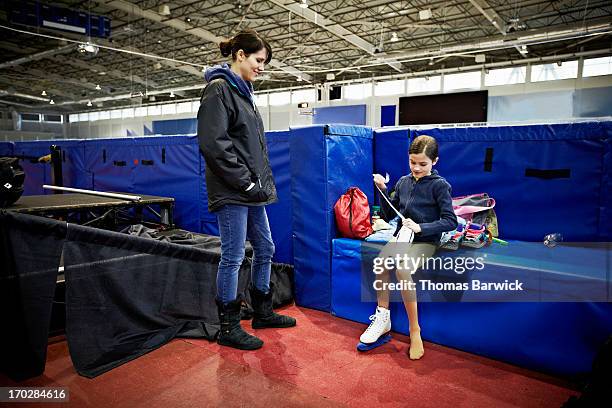 coach watching young figure skater lace up skates - figure skating child stock pictures, royalty-free photos & images