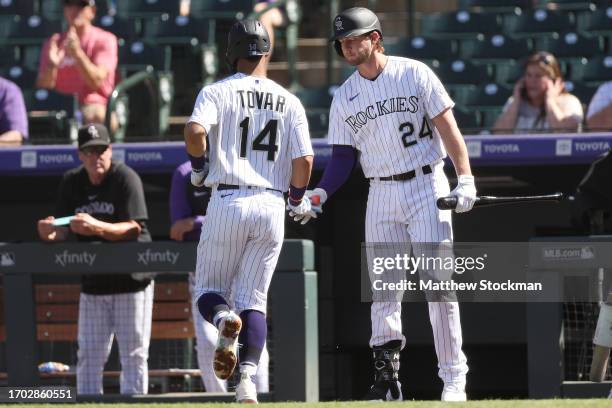 Ezequiel Tovar of the Colorado Rockies is congratulated by Ryan McMahon after scoring on a Kris Bryant double against the Los Angeles Dodgers in the...