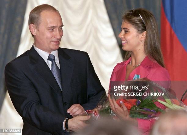 Russian President Vladimir Putin hands flowers to Alina Kabayeva, Russian rhytmic gymnastics star and Olympic prize winner, after awarding her with...