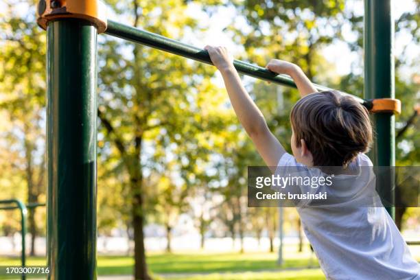 6 year old boy doing sports training on the playground - horizontal bar stock pictures, royalty-free photos & images