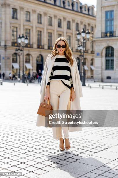 Influencer Alexandra Lapp, wearing a Marc Aurel double breasted coat in creme, a Marc Aurel striped shirt in creme and black, Marc Aurel pants in...