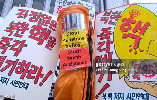 South Korean protester wears a protective suit with anti-North Korean signs taped to the front while holding other signs which read, "North Korean...