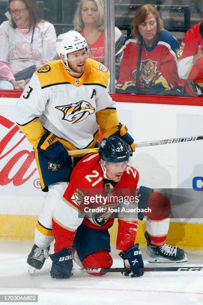 Jeremy Lauzon of the Nashville Predators checks Nick Cousins of the Florida Panthers to the ice during a preseason game at the Amerant Bank Arena on...