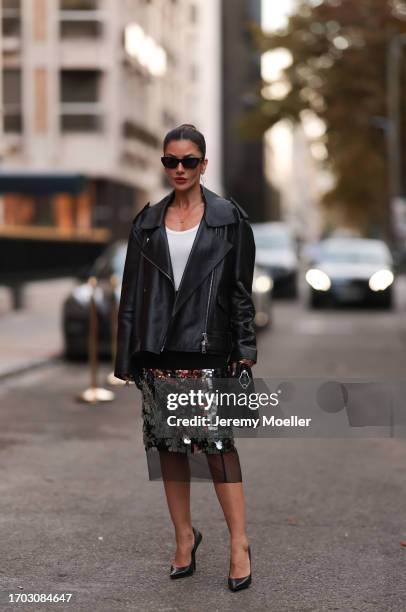 Füsun Lindner is seen wearing black sunglasses from Bottega Veneta, silver twisted earrings from Ole Lyngaard, a golden necklace, a black leather...