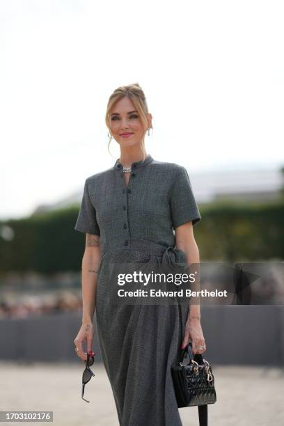 Chiara Ferragni wears sunglasses, a gray midi long dress with short sleeves, a black leather quilted rectangular bag, fishnet tights, outside Dior,...