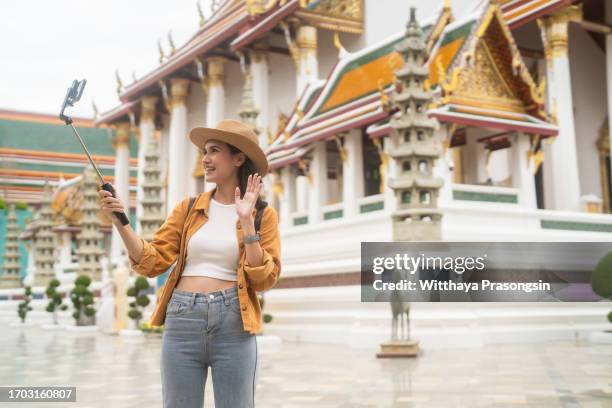 a beautiful young woman uses a mobile phone to take a selfie video of herself with an attractive smile. - zen sable stock pictures, royalty-free photos & images