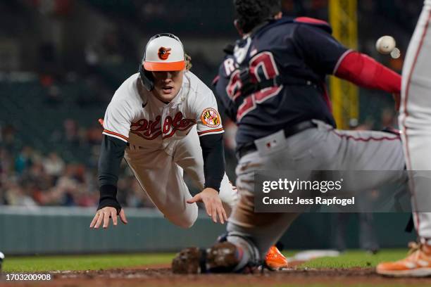 Gunnar Henderson of the Baltimore Orioles slides to steal home plate during the eighth inning against Keibert Ruiz of the Washington Nationals at...