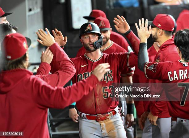 Christian Walker of the Arizona Diamondbacks is congratulated by teammates in the dugout after scoring in the fifth inning against the Chicago White...