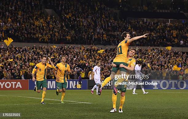 Robbie Kruse of the Socceroos gets lifted up by Brett Holman as he celebrates a goal during the FIFA World Cup Qualifier match between the Australian...