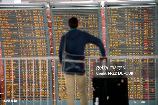 Passenger checks a board which shows departing flights, many of which are cancelled, on June 11, 2013 at Roissy Charles de Gaulle international...
