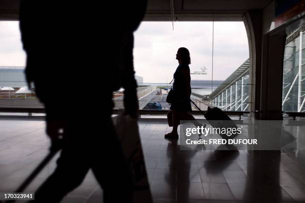 Passengers tote their bags at Roissy Charles de Gaulle international airport, in Roissy-en-France, outside of Paris on June 11, 2013. Hundreds of...