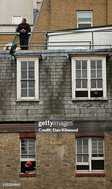 Activists look through windows as a policeman stands guard on the rooftop of the convergence centre of the Stop G8 protest group off Beak Street...