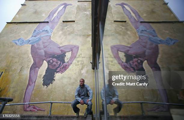 Artist Cosmo Sarson sits besides a giant mural of Jesus breakdancing that he has painted on the 8.5 metre wall beside The Canteen in Stokes Croft and...