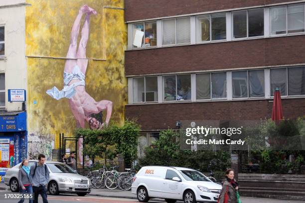 People walk past artist Cosmo Sarson's mural of Jesus breakdancing that he has painted on the 8.5 metre wall beside The Canteen in Stokes Croft and...