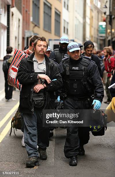 Policeman escorts a man in handcuffs away from the scene where activists occupied a convergence centre of the Stop G8 protest group off Beak Street...